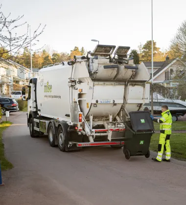 Mises sopbil med två chaufförer som tömmer ett fyrfackskärl i gryningen 