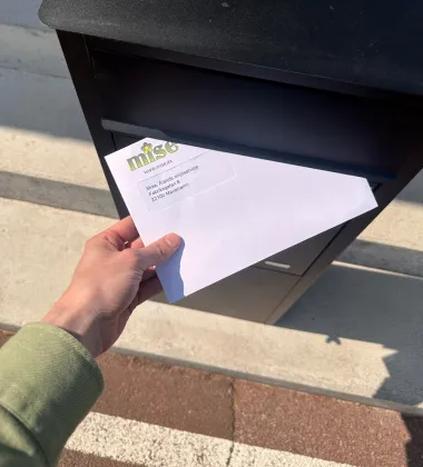 misefaktura som postas i en postlåda av en hand 