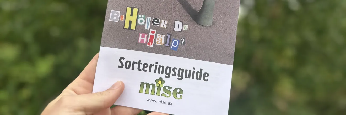Mises broschyr mot grönskande bakgrund